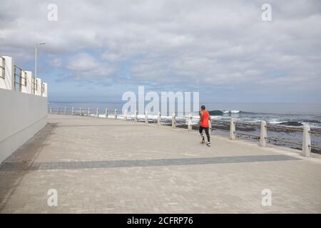 Vista posteriore di un uomo con gamba protesica che corre sul passeggiata Foto Stock