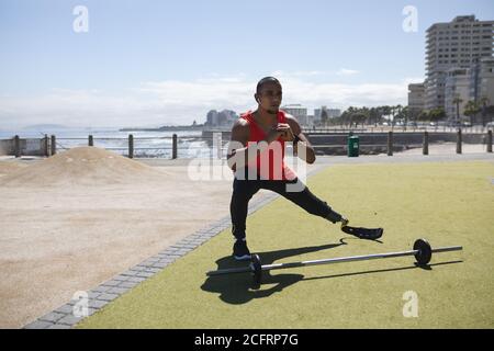 Uomo con gamba protesica che esegue esercizi di stretching nel parco Foto Stock