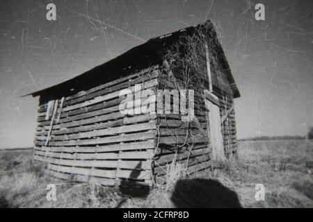 Bella fotografia in bianco e nero degli anni '70 di una vecchia cabina malata e malata in piedi nei campi. Foto Stock