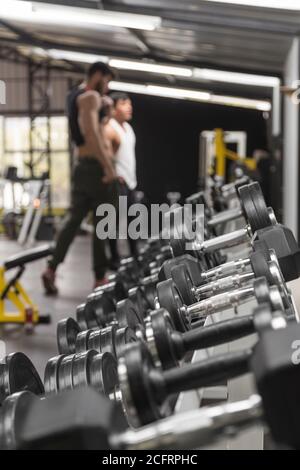 diversi pesi di diverse dimensioni all'interno di una palestra, in background persone di formazione Foto Stock