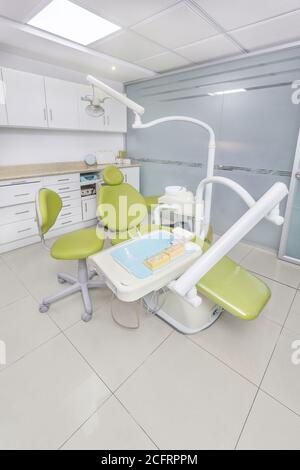 bella sedia da ufficio dentale verde con strumenti medici intorno, primo piano Foto Stock