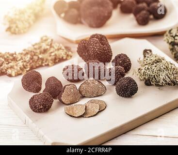 Funghi al tartufo nero, interi e tagliati a fette su tagliere Foto Stock