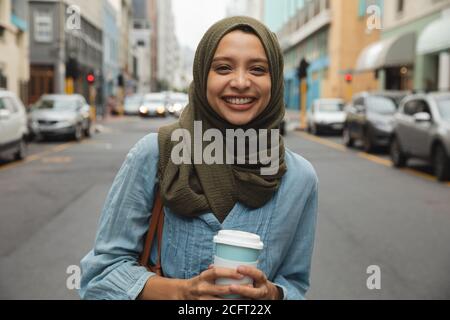 Ritratto di donna in hijab con tazza di caffè sorridente la strada Foto Stock