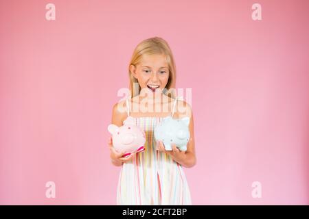 Sorprende bella ragazza bionda che mostra due banche piggy Foto Stock