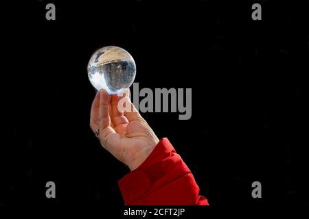 Una donna che tiene una sfera di cristallo nelle sue dita con un riflesso da York Minster, York, North Yorkshire, Inghilterra, Regno Unito. Foto Stock