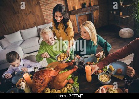 Sopra la vista ad alto angolo di bella attraente allegro attento adorabile famiglia genitori nonni che mangiano casalingo tacchino raccolto servendo asilo nido a. Foto Stock