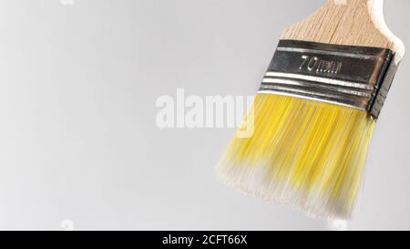 Un pennello su uno sfondo bianco con un posto per il testo per dipingere pareti e oggetti con vernice. Attrezzi per la riparazione. Foto Stock