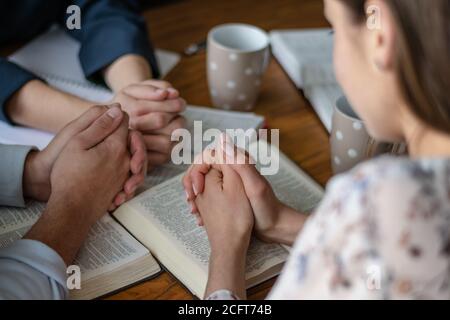 Culto e lode cristiani. Amici felici che pregano e leggono insieme la bibbia. Foto Stock