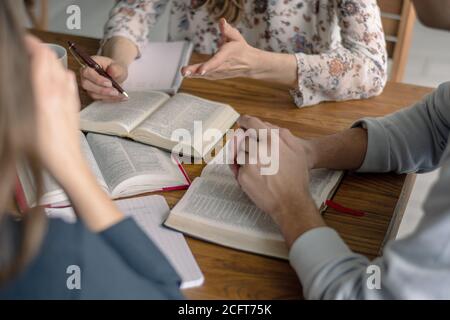 Culto e lode cristiani. Amici felici che pregano e leggono insieme la bibbia. Foto Stock