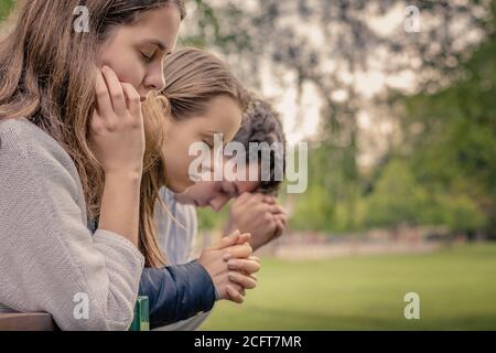 Culto e lode cristiani. Amici felici che pregano insieme nel parco. Foto Stock