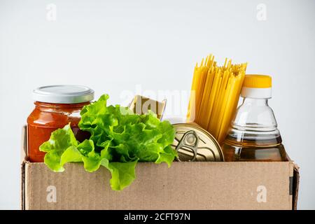 Scatola di donazione con cibo su sfondo bianco. Consegna di prodotti alimentari essenziali. Posiziona per il testo. Foto Stock