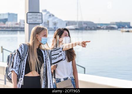 giovane bionda caucasica che punta con il dito qualcosa a. un amico indiano su un porto Foto Stock