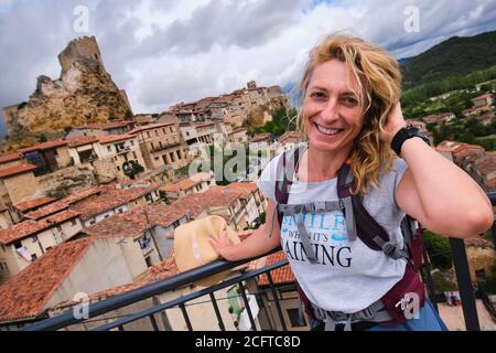 Giovane donna turistica matura con un cappello in un punto di vista di fronte a una città. Foto Stock