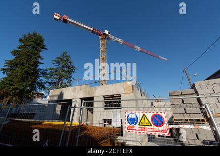 Cantiere in Francia con gru, cielo blu chiaro, vista ad angolo basso. Segno che dice in francese: 'Danger, nessun accesso pubblico al cantiere' Foto Stock