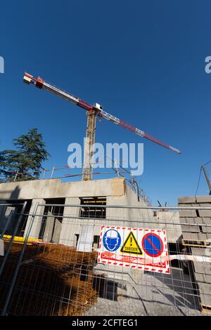 Cantiere in Francia con gru, cielo blu chiaro, vista ad angolo basso. Segno che dice in francese: 'Danger, nessun accesso pubblico al cantiere' Foto Stock