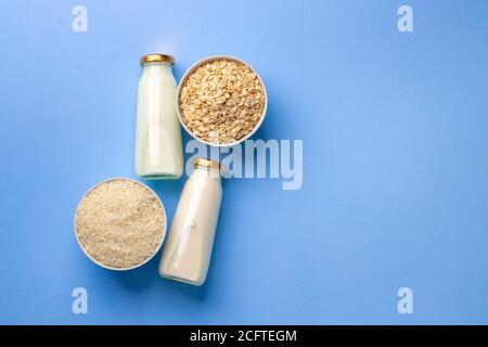 Latte di avena e riso vegano in bottiglie di vetro blu sfondo Foto Stock