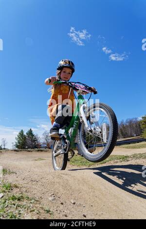 Una bambina (5 anni) schioccando una ruota sulla sua bici Foto Stock