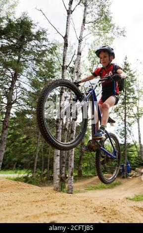 Un ragazzino (8 anni) saltando sulla sua mountain bike Foto Stock