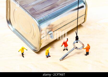 Operatore in miniatura con una gru per manovrare la chiave per una lattina di manzo corned può aprire il concetto Foto Stock