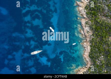Vista dall'alto, splendida vista aerea di alcune barche che galleggiano su un'acqua turchese e limpida. Sardegna, Italia. Foto Stock