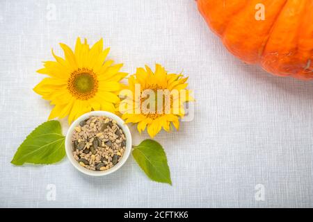 Splendidamente decorata natura morta, layout su sfondo bianco, girasole, zucca, semi in un piatto bianco. Foto di alta qualità Foto Stock