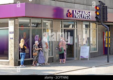 Maschera facciale Covid 19 indossata da Nat West Bank all'aperto clienti di social distancing in coda per entrare in una pandemia di coronavirus della filiale Brentwood Essex Inghilterra Regno Unito Foto Stock