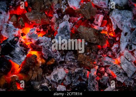 Carboni brucianti. Primo piano di carbone decadente, stagione barbecue. Lampi luminosi di fiamme. Calici caldi e legno bruciati di notte. I carboni rossi bruciano Foto Stock