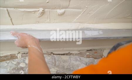 Lo strumento Provila viene applicato alla parete. La soluzione viene applicata alla parete con un attrezzo speciale. Lavoratore applicato con una spatola a una soluzione di Foto Stock