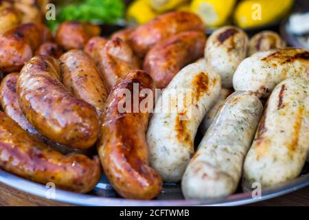 Salsiccia fresca e hot dogs grigliare all'aperto su un barbecue a gas grill. Foto Stock