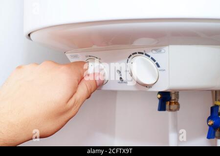 L'operatore accende l'interruttore sul pannello di controllo del riscaldatore dell'acqua elettrico domestico (caldaia). Foto Stock