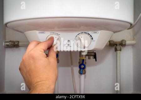 L'operatore accende l'interruttore sul pannello di controllo del riscaldatore dell'acqua elettrico domestico (caldaia). Foto Stock