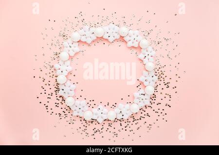 Cornice rotonda di Natale fatta di fiocchi di neve bianco su sfondo rosa. Composizione natalizia, carta da parati. Disposizione piatta, vista dall'alto Foto Stock