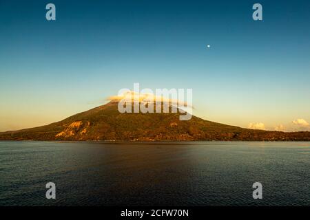 Isola vulcanica indonesiana dietro un sipario di nuvole, Isole Sunda, Indonesia Foto Stock