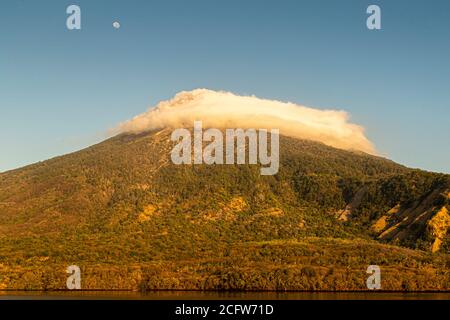 Isola vulcanica indonesiana dietro un sipario di nuvole, Isole Sunda, Indonesia Foto Stock