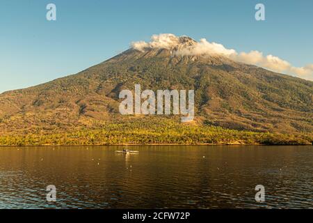 Isola vulcanica indonesiana dietro un sipario di nuvole, Isole Sunda, Indonesia Foto Stock