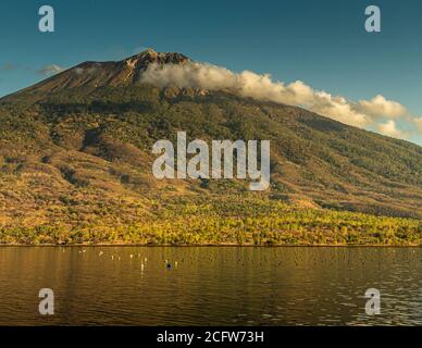 Isola vulcanica indonesiana dietro un sipario di nuvole, Isole Sunda, Indonesia Foto Stock