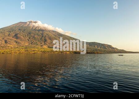 Isola vulcanica indonesiana dietro un sipario di nuvole, Isole Sunda, Indonesia Foto Stock