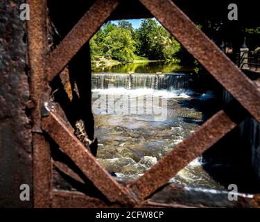 Una vista unica di un fiume e di una cascata attraverso una fessura in una vecchia recinzione a Chagrin Falls, Ohio Foto Stock