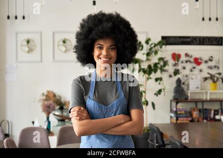 Happy African young woman cafe small business owner standing arms crossed. Foto Stock