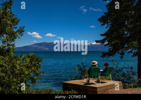 Due persone si rilassano in sedie a sdraio su una piattaforma panoramica che si affaccia sul lago Tahoe al Sugarpine state Park, California Foto Stock