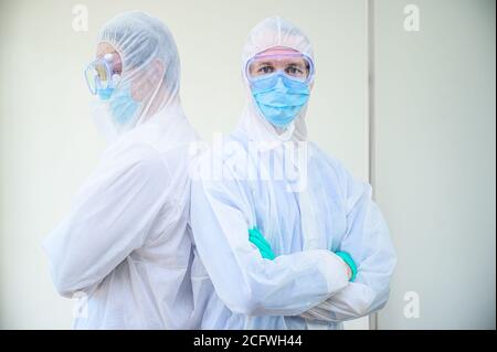 Un paio di scienziati maschi che indossano tuta protettiva si trovano sullo sfondo bianco del laboratorio. Ritratto dello scienziato Foto Stock