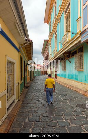 Uomo ecuadoriano che cammina in una colorata strada in stile coloniale, Guayaquil, Ecuador. Foto Stock