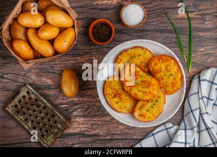 Panini con patate fritte e cipolle verdi. Delizioso antipasto in stile rustico. Pane, sale, pepe e patate crude sul tavolo. Foc. Selettivo Foto Stock