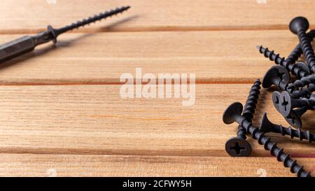 Un cacciavite e una lama autosforante su fondo di legno marrone. Strumenti di costruzione per riparare la casa. Foto Stock