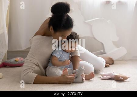 Giovane madre afroamericana che si prende cura di giocare giocattoli con il bambino. Foto Stock