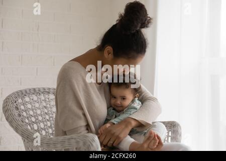 Amore giovane donna mista razza baciare piccolo adorabile bambino. Foto Stock