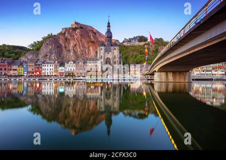 Dinant, Belgio. Immagine del paesaggio urbano della bella città storica di Dinant con il riflesso della città nel fiume Mosa al tramonto estivo. Foto Stock