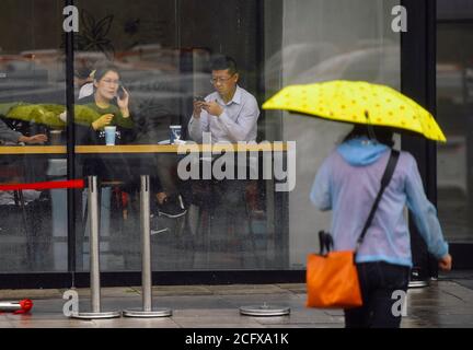 Changchun, Jilin, Cina. 8 Settembre 2020. La gente prende riparo dalla pioggia innescata dal tifone Haishen in un coffee shop a Changchun, Provincia di Jilin della Cina nordorientale, 8 settembre 2020. La pioggia pesante ha colpito la maggior parte delle parti della città di Changchun da Lunedi notte a Martedì alimentato dal tifone Haishen, il decimo tifone di quest'anno. Lunedì, la sede centrale cinese per il controllo delle alluvioni e il soccorso alla siccità ha aggiornato la risposta alle emergenze per il controllo delle inondazioni e dei tifoni dal livello IV al livello III Credit: Xinhua/Alamy Live News Foto Stock