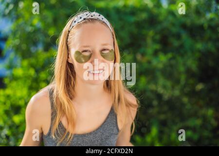 Donna sorridente che applica le macchie di cura degli occhi di idrogel, pelle idratante sotto gli occhi, godendo le procedure di cura della pelle Foto Stock