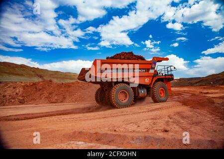 Estrazione e trasporto di minerali di alluminio.. Estrazione a taglio aperto (cava). Dumper da cava Hitachi arancione con argilla bauxite. Foto Stock